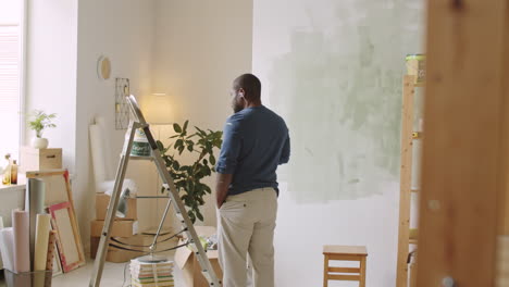man painting a wall in a room under renovation