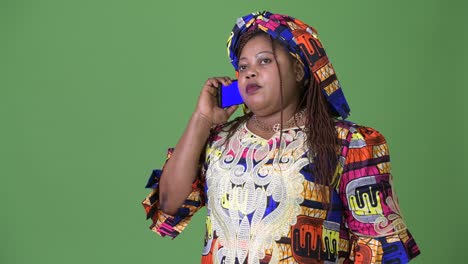 overweight beautiful african woman wearing traditional clothing against green background