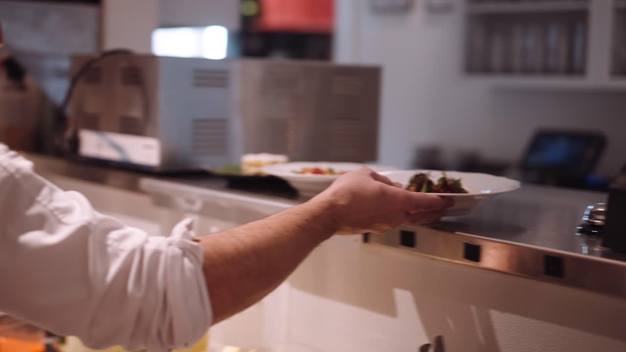 el cocinero masculino pone el plato preparado en el mostrador para que se pueda servir el plato