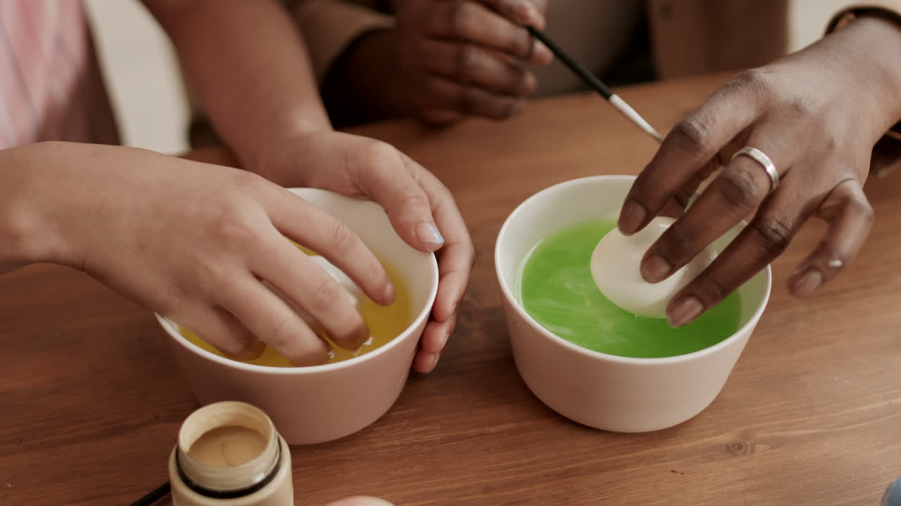 manos de personas irreconocibles coloreando huevos