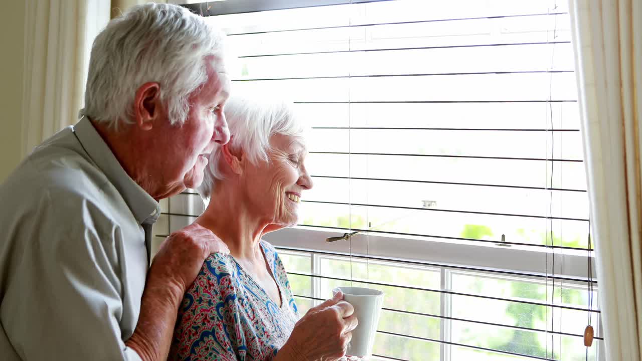 시니어 커플이 창문 밖을 보고 있습니다.