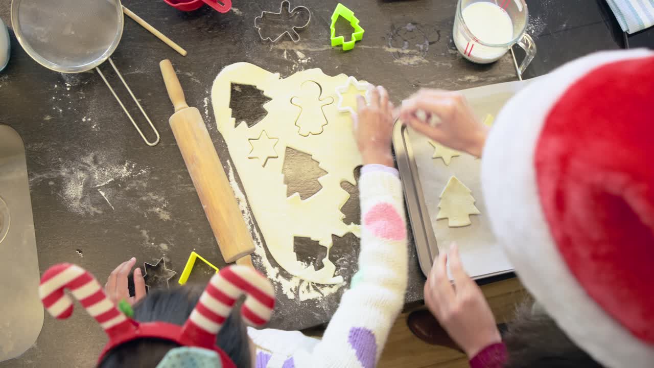 I pasticceri imprimono forme di biscotti nell'impasto dopo che una bambina ha scelto una formina verde per la preparazione natalizia.