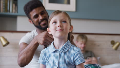 same sex male couple at home getting daughter ready for school plaiting her hair