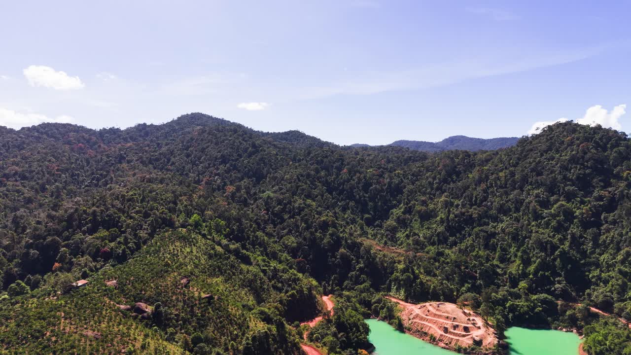 La vista mostra alte colline e montagne a Lam Dong, Vietnam. L'area è ricca di vegetazione e uno specchio d'acqua limpida. Il cielo luminoso aggiunge bellezza al paesaggio