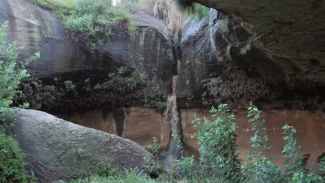 muddy waterfall shows effect of erosion, cutting deep cleft in rock