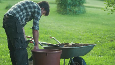 young man sifting soil pouring rocks into bucket