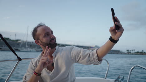 man takes selfie with peace sign on a boat