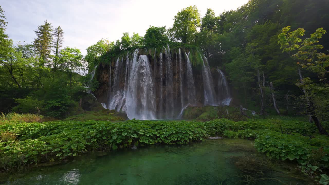 Scenic Plitvice waterfall crashing into bright blue lake in UNESCO natural heritage site, Croatia
