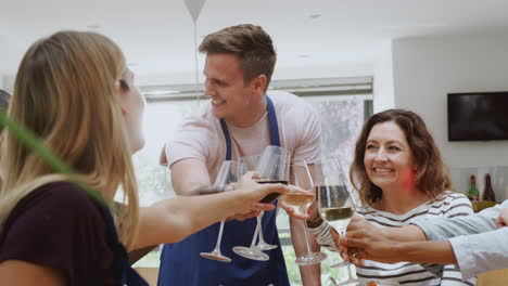 groep mannen en vrouwen die toast maken terwijl ze genieten van het eten van een maaltijd die in de keuken is bereid