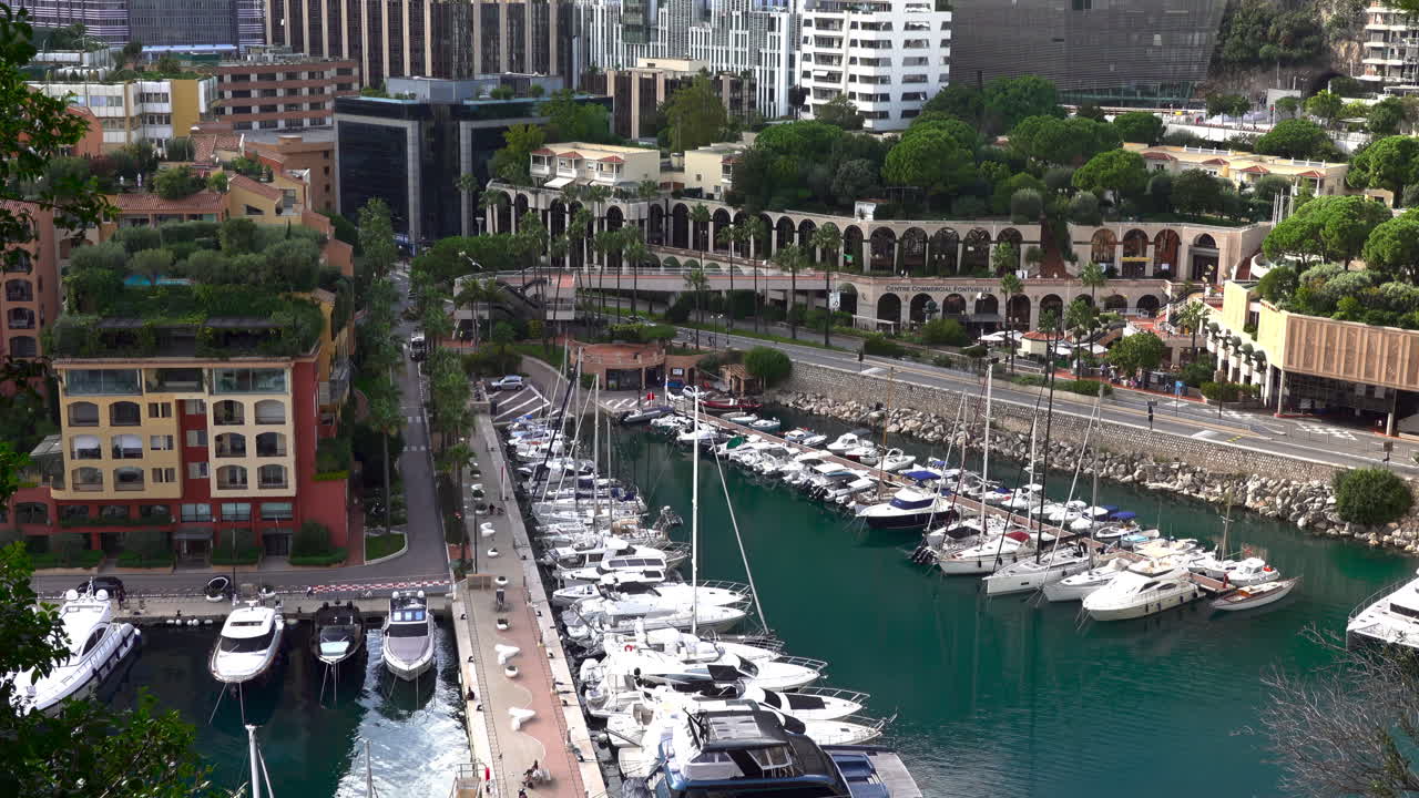 High-angle view of Port de Fontvieille in Monaco, showcasing colorful buildings, luxury yachts, and the surrounding mountainous landscape