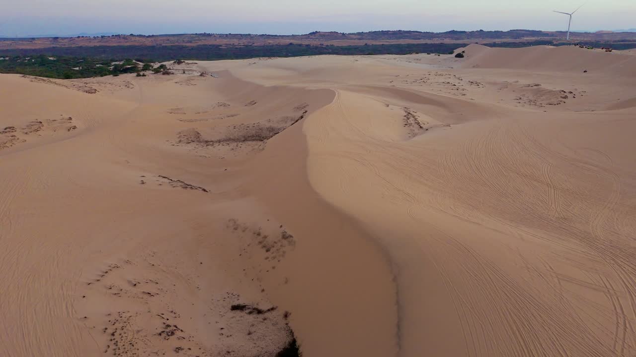 Natural sand dunes valley forming abstract wave shapes and warm colors during sunrise over the Vietnamese landscape.