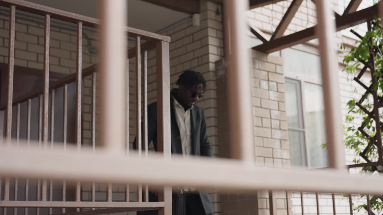 Long shot shows man with dreadlocks scratching head while checking wrist watch, worried about time, steady walk resumes down hallway, urgent mood captured with clean lines and minimal background