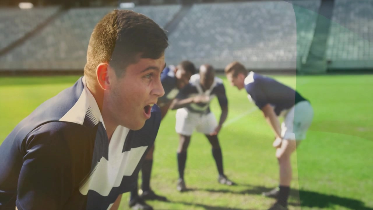 Giocatore di rugby che alza la testa, inspirando, chiamando i compagni di squadra sul campo in erba, radunando la squadra per la prossima azione.