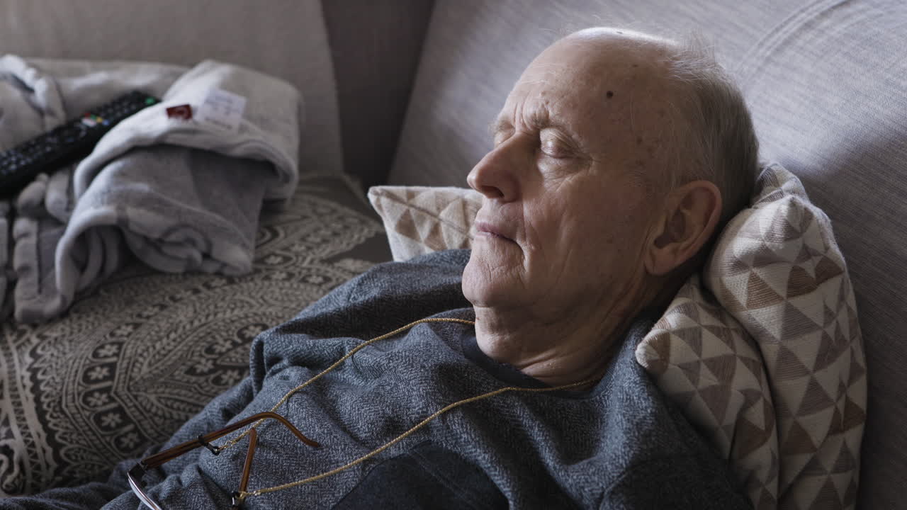Eldre mann sover på en sofa