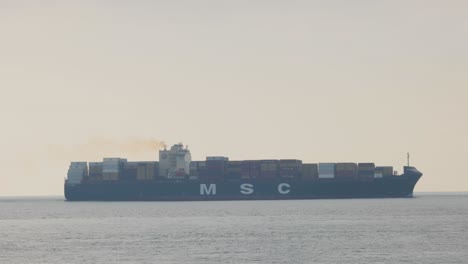 large container ship emitting smoke while sailing