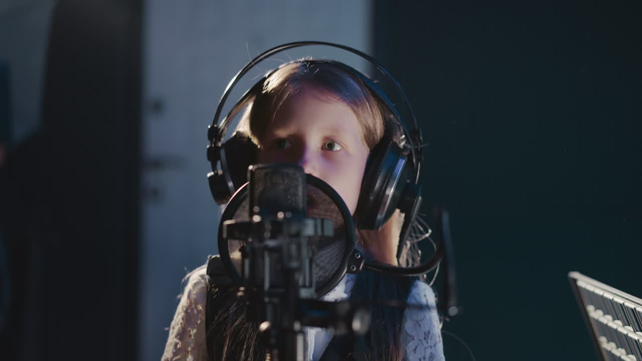 Vocalist moves hand while singing closeup. Child catches beat while recording song in recording studio. Skilled kid wearing headphones in audio studio