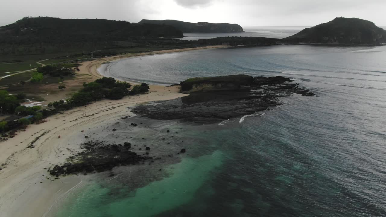 Tanjung Ana beach from high above with a motorbike traveling quickly on the sand below. Aerial