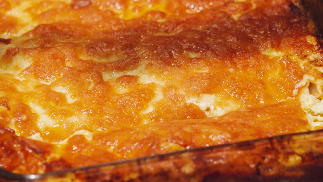 Knife Cutting into Crispy Golden Melted Cheese Lasagna Top. Cooked Italian Dish Ready to Portion and Serve After Cooking in Hot Oven. Bolognese Sauce Filled Pasta Based Food