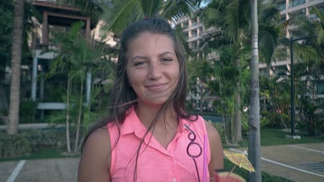 attractive-girl-with-cocktail-in-hand-smiles-against-palms