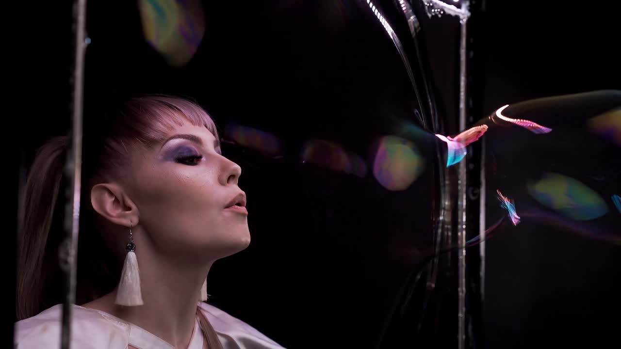 una chica bonita hace trucos con burbujas de jabón ella sopla una burbuja a través de la cortina de jabón