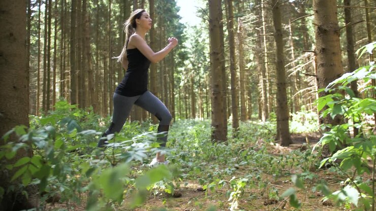 Donna che inizia a correre attraverso un'area boschiva con un passo lungo e saltellante