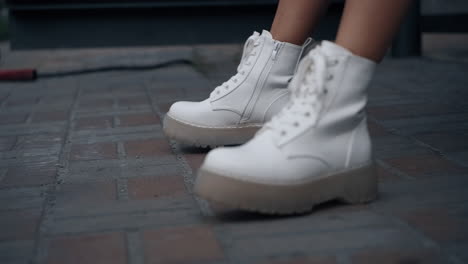 white shoes legs moving on ground in urban city. woman wearing shoes in town.