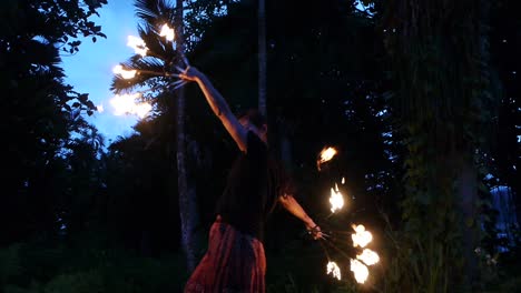 asian woman performing fire dance with spinning fire fans in long and slow movement