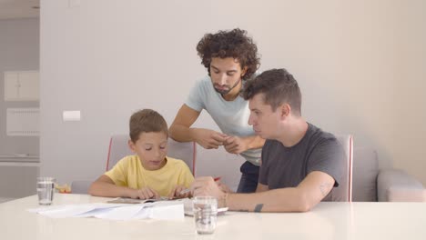 dos padres ayudando a un niño concentrado con las tareas escolares
