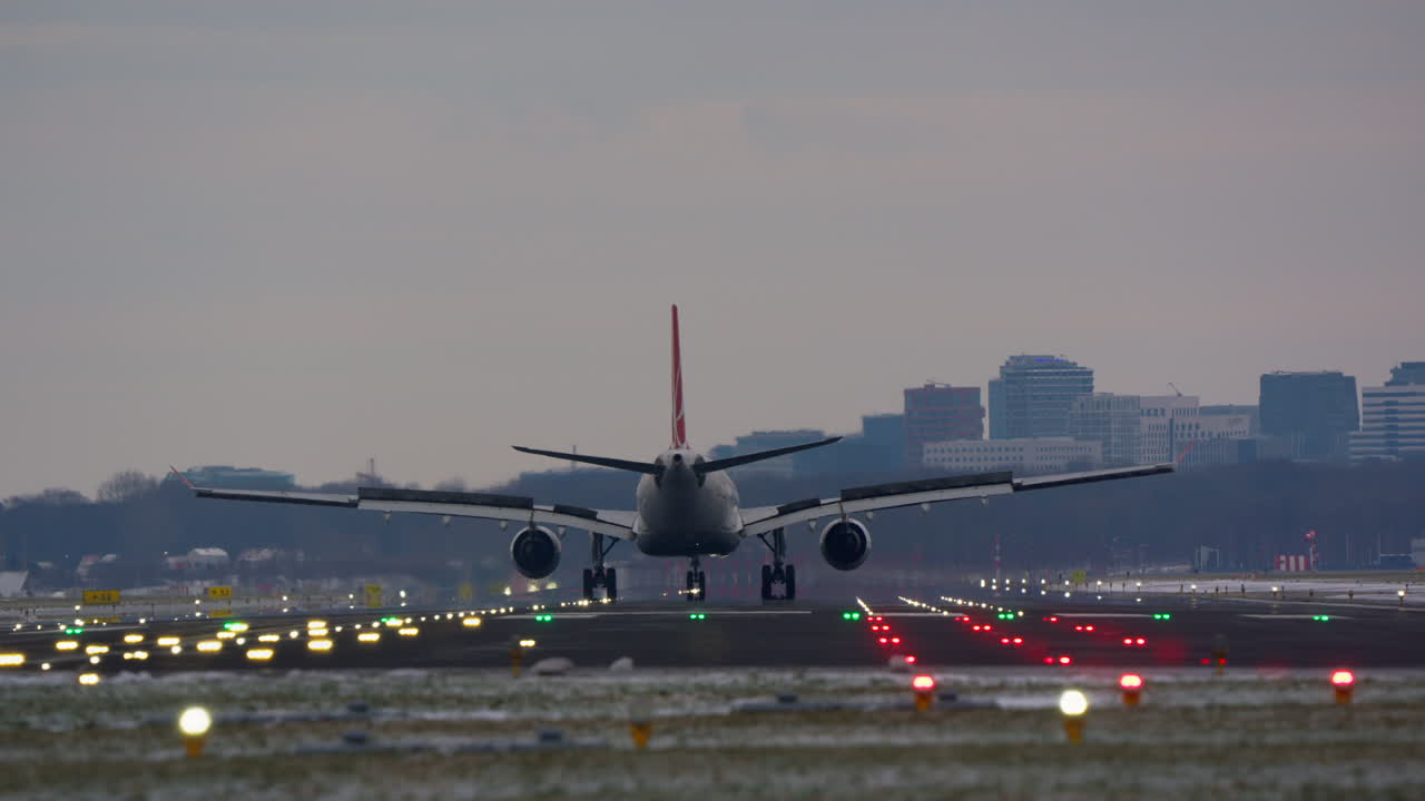 Gran avión de pasajeros aterrizando en pista de aeropuerto iluminada al anochecer