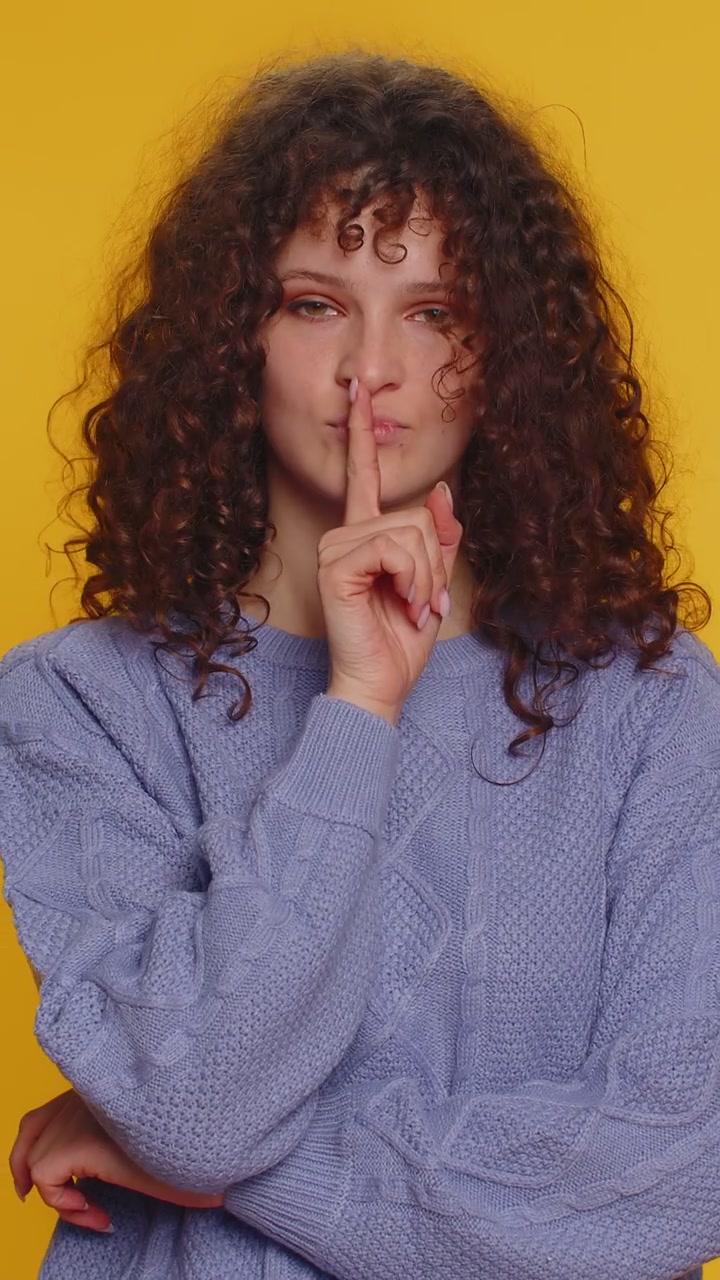 Giovane donna preme l'indice sulle labbra fa silenzio gesto segno non dice segreto shh stare zitto