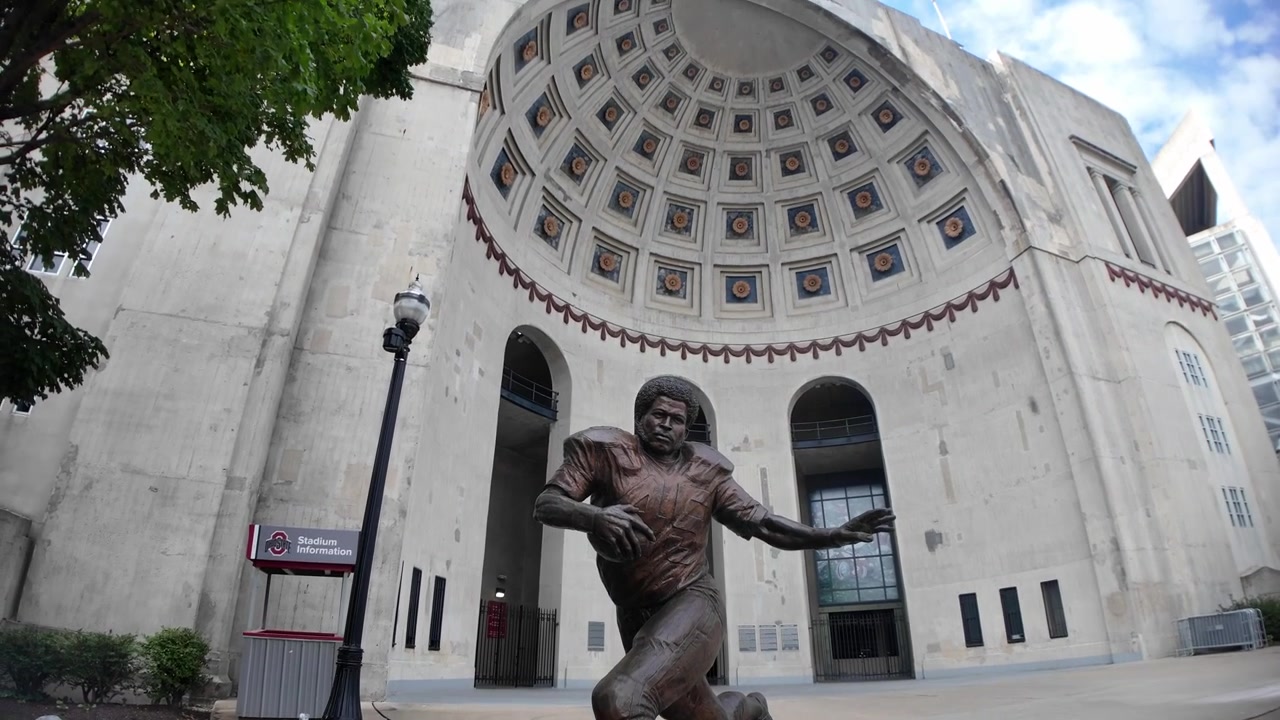 Statua di Archie Griffin all'Ohio Stadium presso l'Università dell'Ohio a Columbus, Ohio, con nuvole bianche e un cielo blu.