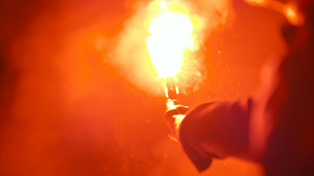 한 남자가 들고 있는 불타는 신호탄의 클로즈업 1