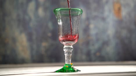 seamless, looping clip of red wine pouring into a rustic glass with blue background