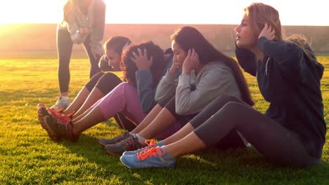 Sporty-women-doing-sit-ups-during-fitness-class