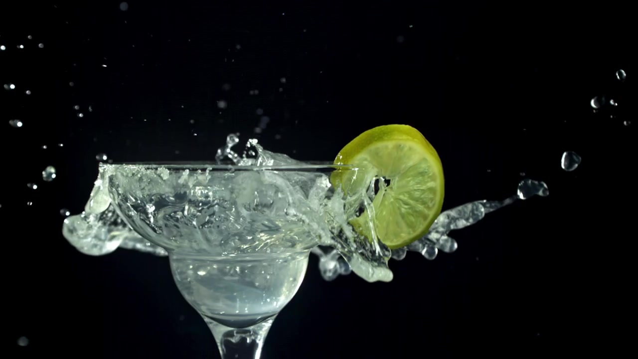 Cubetti di ghiaccio che si tuffano in un cocktail Margarita con lime e bordo di sale