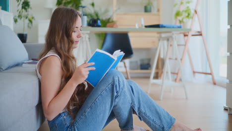 female student studying for exam by sofa on floor