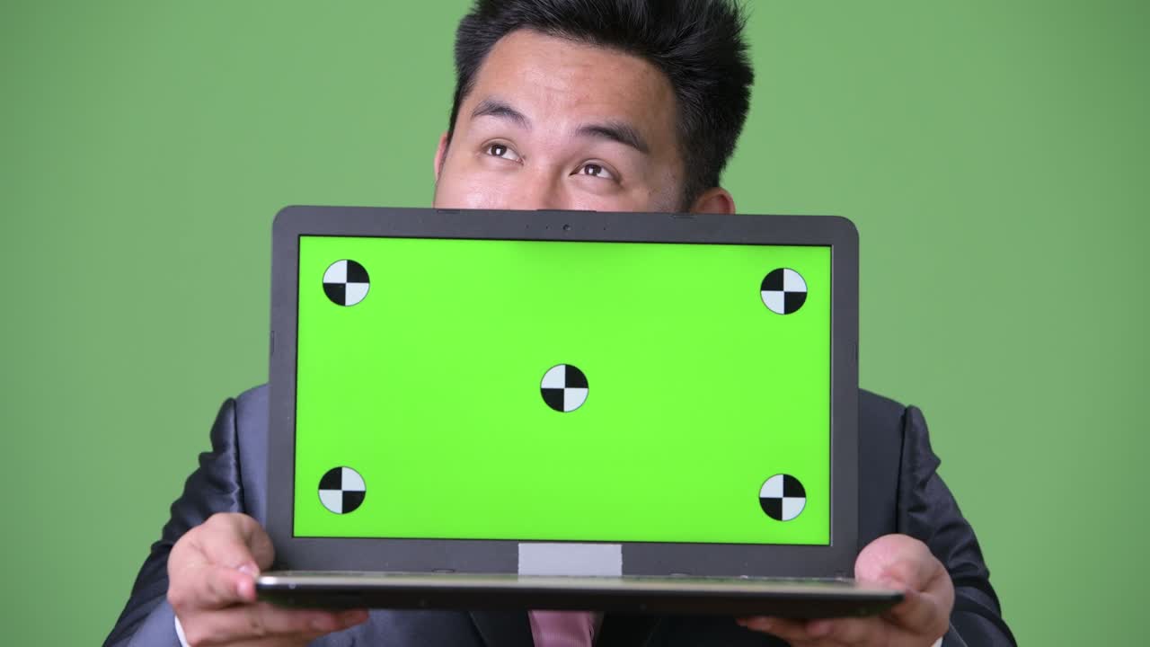 초록색 배경에 젊은 잘생긴 과체중 아시아 사업가