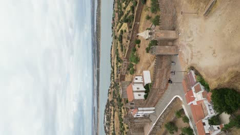 Vídeo-Vertical-Del-Castillo-De-Mourao,-Lago-Panorámico-De-Fondo,-Toma-Aérea-En-órbita