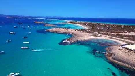 sailboat stranded on cliff near the coast of formentera island, spain, during a summer sunny day. unbelievable aerial view flight descending drone