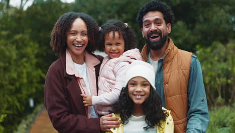 una feliz familia de cuatro personas sonriendo en el parque