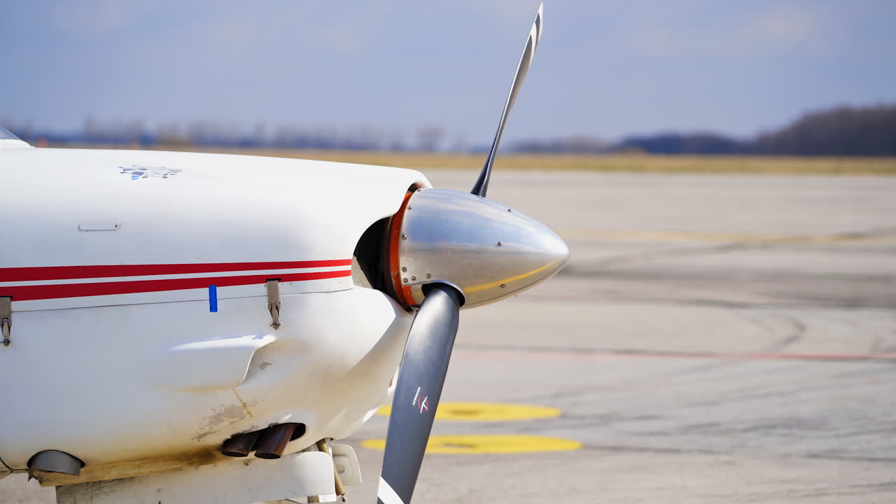 Front part of the little plane. Propeller starts to rotate. Aircraft on the empty aerodrome.