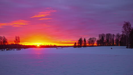 Red-and-orange-sky-with-moving-clouds-over-flat-snowy-landscape