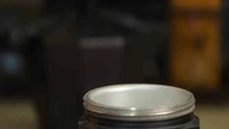 un primer plano de la parte inferior de una cafetera de espresso con una persona que agrega el filtro y el café