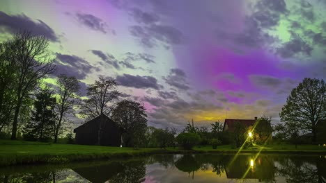 aurora borealis shine through the clouds in a dreamy time lapse above a countryside cabin