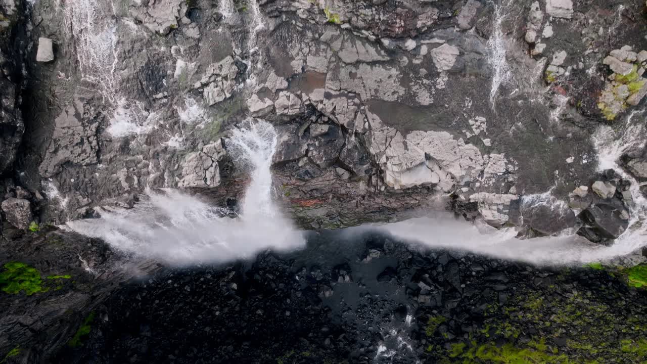 costa rocosa de las islas feroe, con cascadas de agua en rocas negras, evocando serenidad, vista aérea