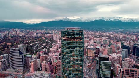 aerial orbit of the titanium tower and the financial and residential center with the snowcapped andes mountains in the background