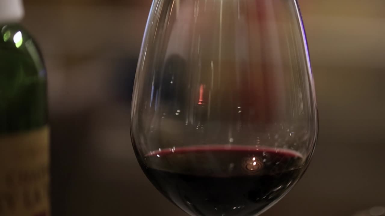 Um close-up detalhado de vinho tinto em uma taça, apresentando reflexos suaves e bokeh.