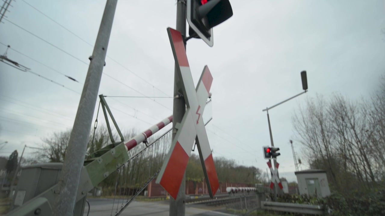Railroad crossing gate and sign with red traffic light on a cloudy day