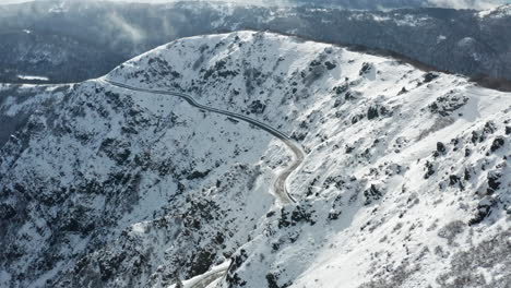 una montaña cubierta de nieve con carreteras sinuosas, capturada durante el día, vista aérea