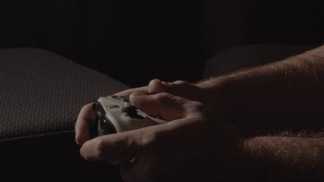 male hands playing relaxed on a videogame controller and pushing buttons